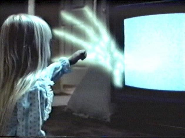 Image from Poltergeist of the young girl touching the hand of a Ghost coming out of the tv
